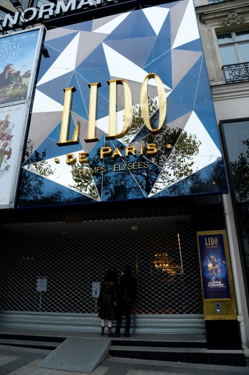 Des passants regardent à travers la devanture fermée du Lido, à Paris, le 14 novembre 2015